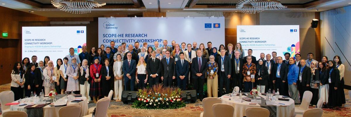 dozens of people standing in front of three banners in a meeting room